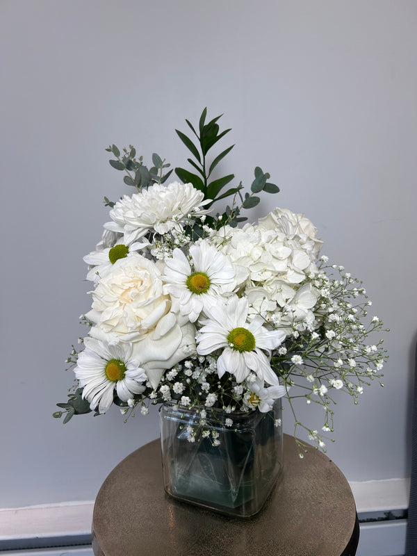 Classic white sympathy arrangement with white hydrangea, roses, chrysanthemums, daisies and baby's breath in a glass cube vase — Flowers Station Winnipeg
