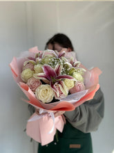 Woman holding roses and lilies bouquet with satin ribbon
